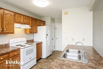 Greenwood house for rent - A kitchen with a stove top oven and a refrigerator.