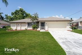 Cape Coral house for rent - a white house with a lawn and a driveway
