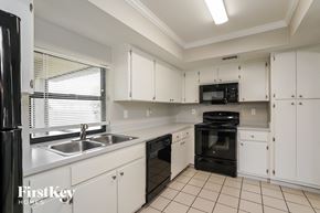 Cape Coral house for rent - a kitchen with white cabinets and black appliances