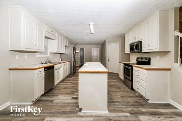 Covington house for rent - a renovated kitchen with white cabinets and white appliances and wood floors