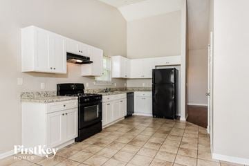 Powder Springs house for rent - A kitchen with white cabinets and black appliances.