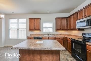 Odenville house for rent - a kitchen with wooden cabinets and granite counter tops and black appliances