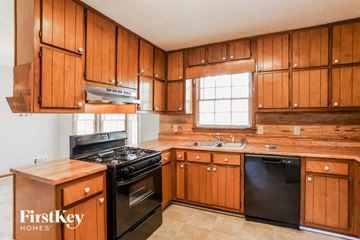 Stockbridge house for rent - a kitchen with wooden cabinets and black appliances