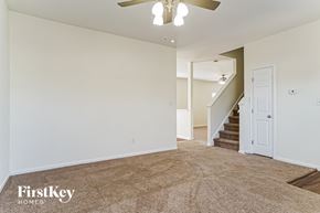 Fuquay Varina house for rent - A spacious room with a carpeted floor and a staircase in the background.