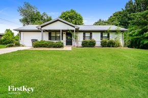 Covington house for rent - A white house with a black door and windows is surrounded by a green lawn.