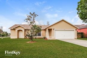 Kissimmee house for rent - a beige house with a garage and a green lawn