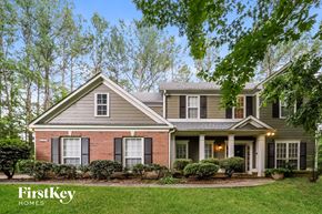 Acworth house for rent - A house with a grey roof and a red brick wall is surrounded by greenery.