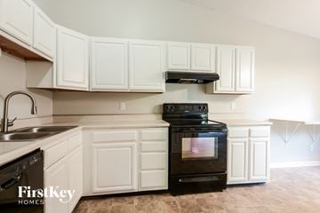 Avon house for rent - A kitchen with white cabinets and a black stove top oven.