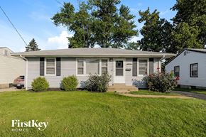 Florissant house for rent - A house with a grey roof and a white door is surrounded by green grass.