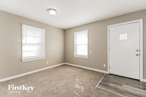 Florissant house for rent - A room with a carpeted floor, a door, and two windows.
