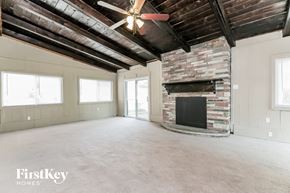 Florissant house for rent - A spacious room with a fireplace and a ceiling fan.