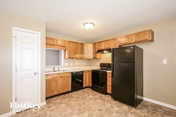 Greenfield house for rent - A kitchen with a black refrigerator and wooden cabinets.