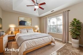 Covington house for rent - A bedroom with a large bed, a ceiling fan, and a potted plant.