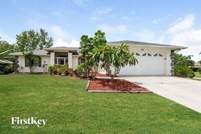 Cape Coral house for rent - a house with a lawn and palm tree in front of it