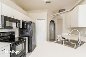 Cape Coral house for rent - a white kitchen with black appliances and a sink