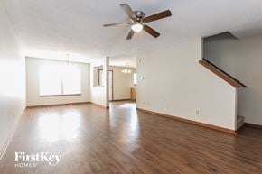Greenwood house for rent - A spacious room with wooden floors and a ceiling fan.