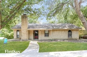 Garland house for rent - the front of a brick house with a sidewalk and a tree