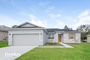 Poinciana house for rent - a white house with a lawn and a driveway