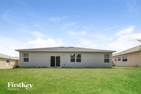 Poinciana house for rent - a small white house with a grass yard in front of it