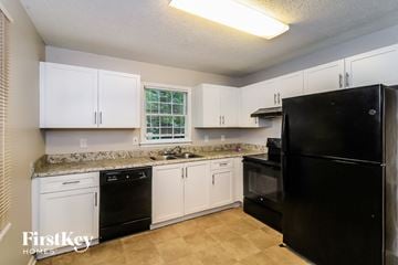 Woodstock house for rent - a kitchen with white cabinets and a black refrigerator