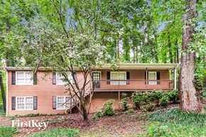 Woodstock house for rent - a house in the woods with trees and a deck