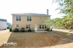Acworth house for rent - a yellow house with a gravel driveway and trees