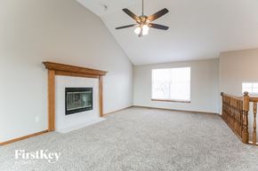 Greenwood house for rent - A spacious room with a fireplace and a ceiling fan.