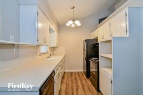 Lee's Summit house for rent - a kitchen with white counters and white cabinets and a black refrigerator