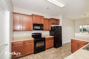 Chelsea house for rent - a kitchen with wooden cabinets and black appliances