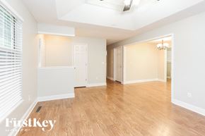 Greenwood house for rent - A spacious room with wooden flooring and white walls.