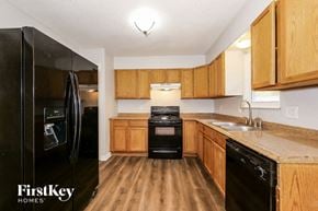 Blue Springs house for rent - a kitchen with black appliances and wooden cabinets