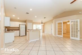 Fort Myers house for rent - A spacious kitchen and living room with white appliances and cabinets.