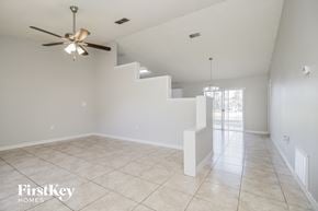 Kissimmee house for rent - A spacious room with a fan and a staircase.