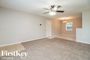 Kissimmee house for rent - A spacious room with a ceiling fan and carpeted floor.