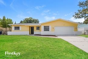 Palm Harbor house for rent - A yellow house with a white garage door and a black door.
