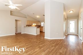 Lehigh Acres house for rent - A spacious room with wooden floors and a ceiling fan.