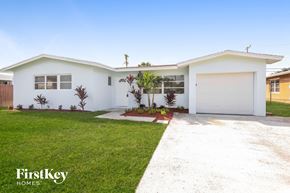 Palm Beach Gardens house for rent - a white house with a lawn and a white garage door