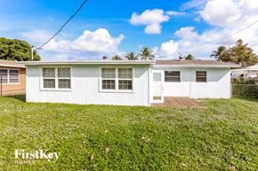 Palm Beach Gardens house for rent - a white house with green grass and a yard
