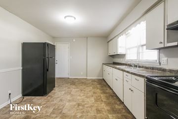 Plainfield house for rent - a kitchen with white cabinets and black appliances and a black refrigerator