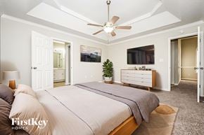 Fayetteville house for rent - A bedroom with a large bed, a ceiling fan, and a dresser with a mirror above it.