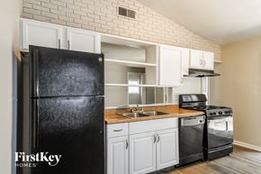 Florissant house for rent - a kitchen with white cabinets and a black refrigerator