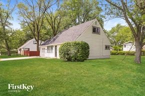 Park Forest house for rent - a small white house with a grassy yard and trees