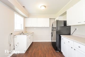 Park Forest house for rent - a white kitchen with white cabinets and a black refrigerator