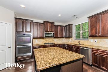 Mcdonough house for rent - a kitchen with granite countertops and wooden cabinets and stainless steel appliances