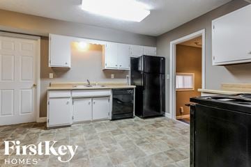 Beech Grove house for rent - a kitchen with white cabinets and a black refrigerator