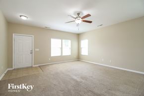 Winston-Salem house for rent - A spacious room with a carpeted floor, a ceiling fan, and a door.