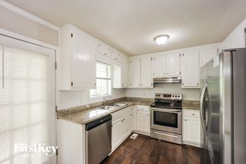 Covington house for rent - a kitchen with white cabinets and stainless steel appliances