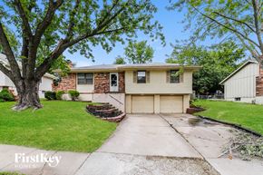Blue Springs house for rent - a white and brick house with a driveway and a tree