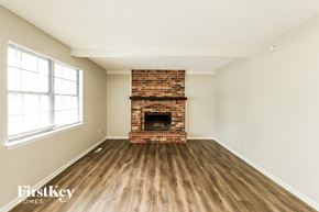 Blue Springs house for rent - an empty living room with a brick fireplace and wooden floors