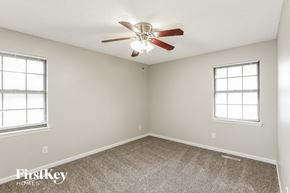 Blue Springs house for rent - a bedroom with a ceiling fan and two windows